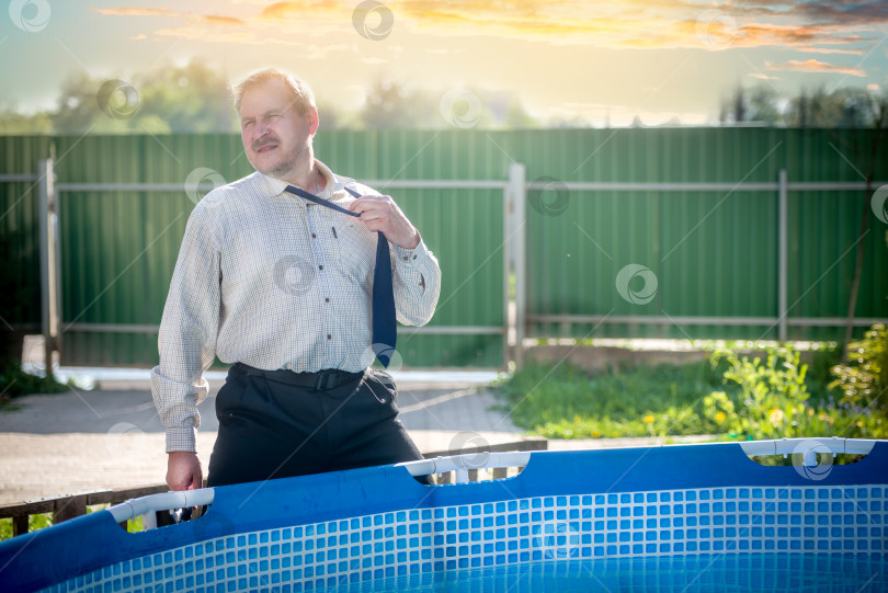Скачать красивый мужчина в деловом костюме страдает от жары у бассейна фотосток Ozero