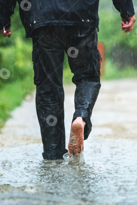 Скачать Мужчина под дождем идет босиком по лужам фотосток Ozero
