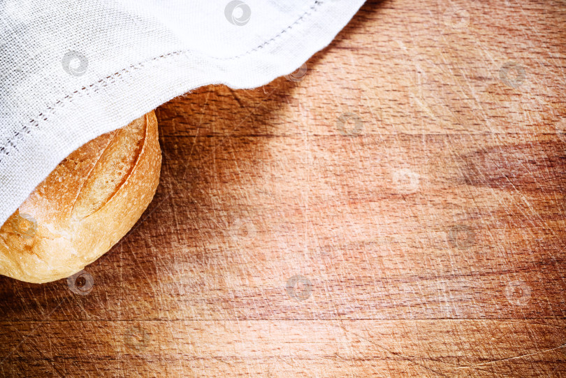 Скачать Свежий хлеб, накрытый льняной салфеткой поверх деревянной фотосток Ozero