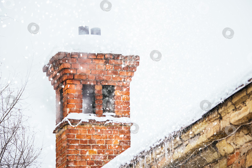 Скачать Старый каменный дом зимой и дым из трубы во время снегопада фотосток Ozero