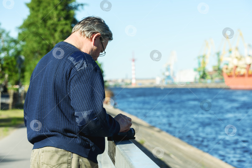 Скачать Россия, Санкт-Петербург, 30 мая 2020 года: Мужчина с видеокамерой на берегу морского порта фотосток Ozero