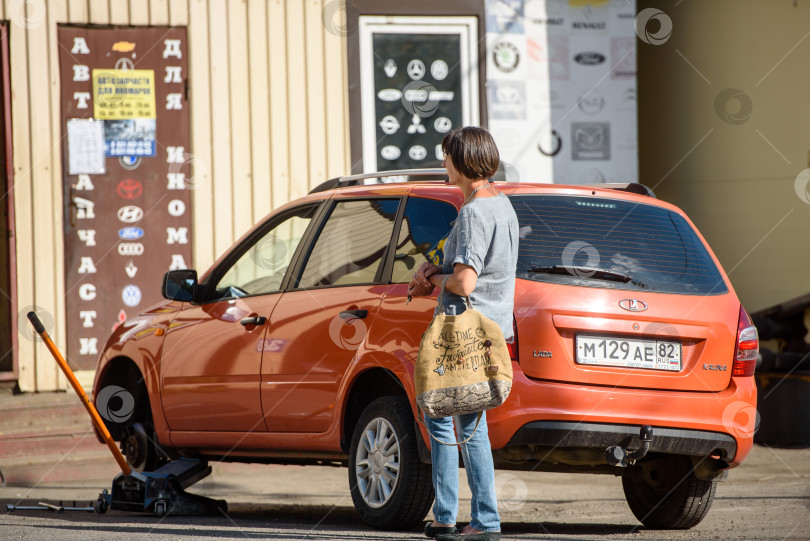 Скачать Россия, Гатчина, 22 июня 2020 года: женщина ждет на станции техобслуживания, чтобы починить свой автомобиль фотосток Ozero