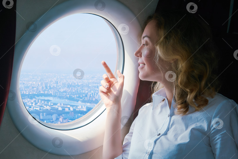 Скачать женщина-пассажир самолета с интересом смотрит на город внизу фотосток Ozero