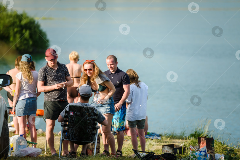 Скачать Россия, Санкт-Петербург, 24 июня 2020 года: группа молодых людей в компании отдыхают на озере и веселятся фотосток Ozero