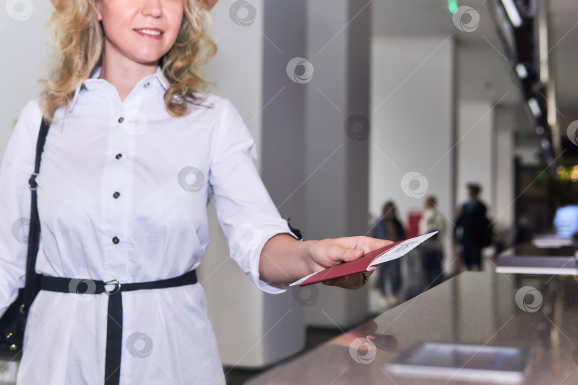 Скачать рука женщины-путешественницы, протягивающей паспорт и авиабилет для прохождения паспортного контроля в аэропорту фотосток Ozero