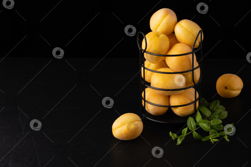 Скачать Свежие абрикосы в корзинке на черном деревянном столе фотосток Ozero