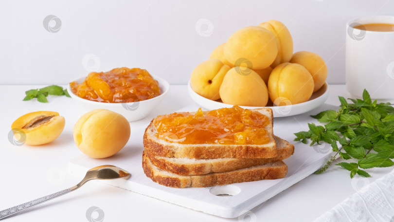 Скачать Тосты из хлеба с абрикосовым джемом и свежими фруктами с мятой на белом деревянном столе. Вкусный завтрак фотосток Ozero