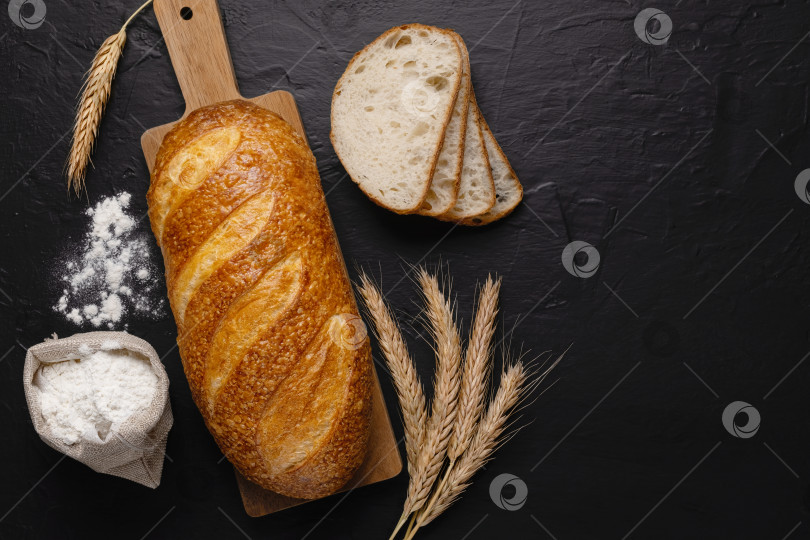 Скачать Свежий пшеничный батон из хлеба и муки на темном фоне.Вид сверху. Пространство для копирования фотосток Ozero