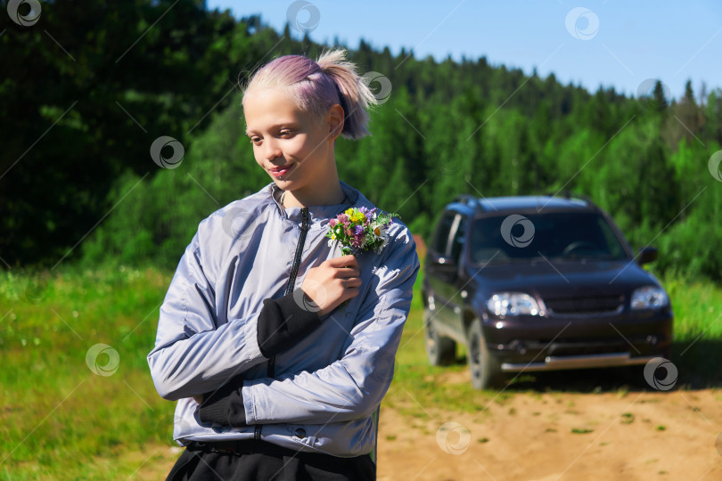 Скачать девушка с букетом полевых цветов на природе на фоне автомобиля фотосток Ozero
