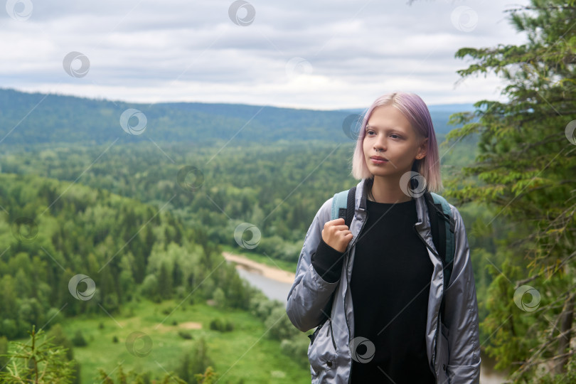 Скачать девочка-подросток с рюкзаком прогуливается по вершине горы на фоне лесистых холмов фотосток Ozero
