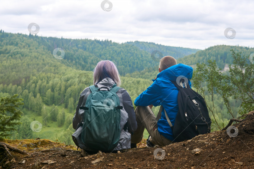 Скачать два подростка с рюкзаками сидят на краю обрыва, глядя на холмы вдалеке фотосток Ozero