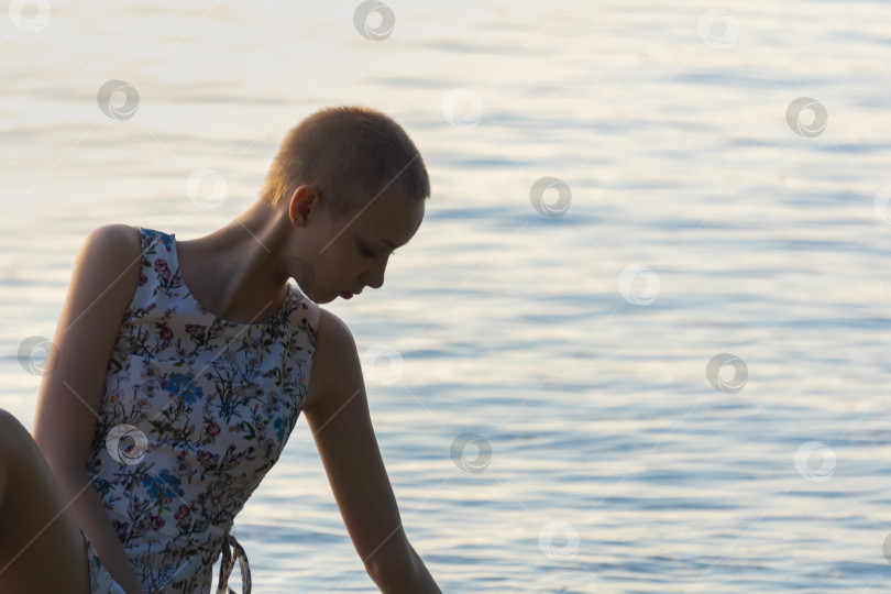 Скачать портрет девочки-подростка с короткой стрижкой в платье на фоне открытой воды фотосток Ozero