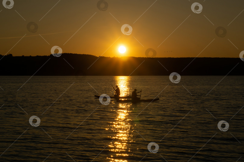 Скачать два серфера на стоячих досках для гребли на фоне заходящего солнца фотосток Ozero