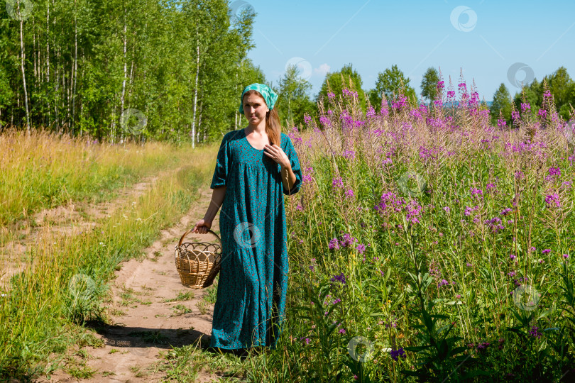 Скачать молодая женщина в народной крестьянской одежде с плетеной корзинкой идет по полевой дороге фотосток Ozero