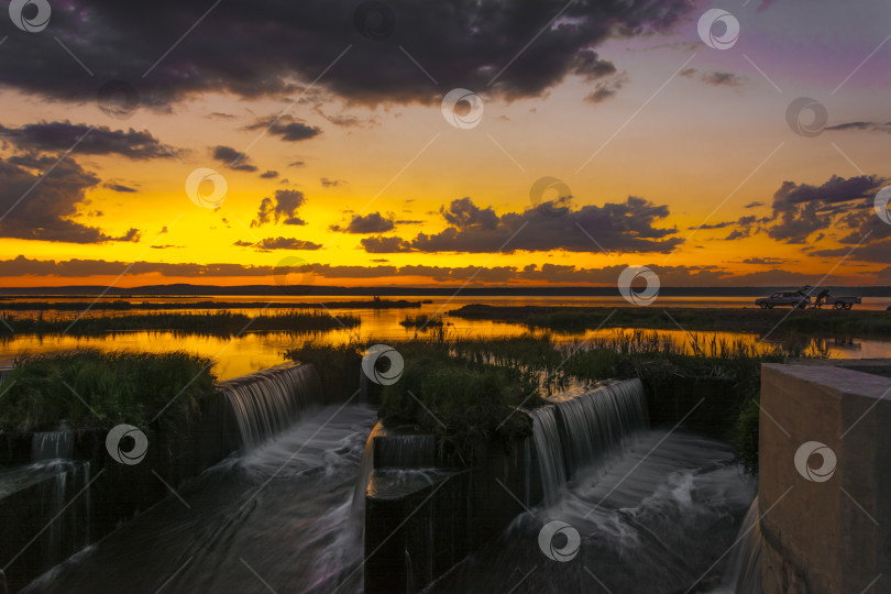 Скачать Искусственный водосброс в лучах заходящего солнца фотосток Ozero