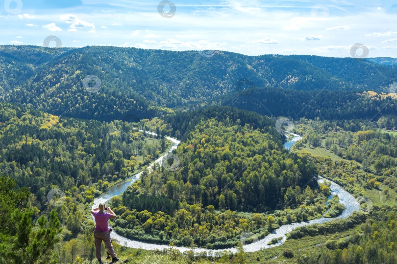 Скачать Турист фотографирует реку текущую среди склонов гор поросших хвойным лесом. фотосток Ozero
