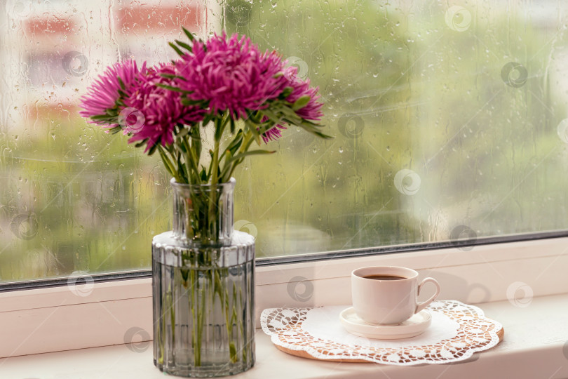 Скачать Чашка кофе и цветы в вазе, стоящей рядом с дождливым окном. фотосток Ozero