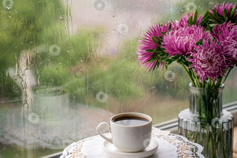 Скачать Чашка кофе и цветы в вазе, стоящей рядом с дождливым окном. фотосток Ozero