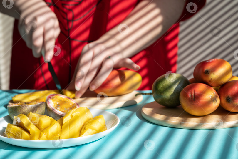 Скачать шеф-повар режет фрукты. Женские руки режут манго и маракуйю, фруктовый завтрак фотосток Ozero