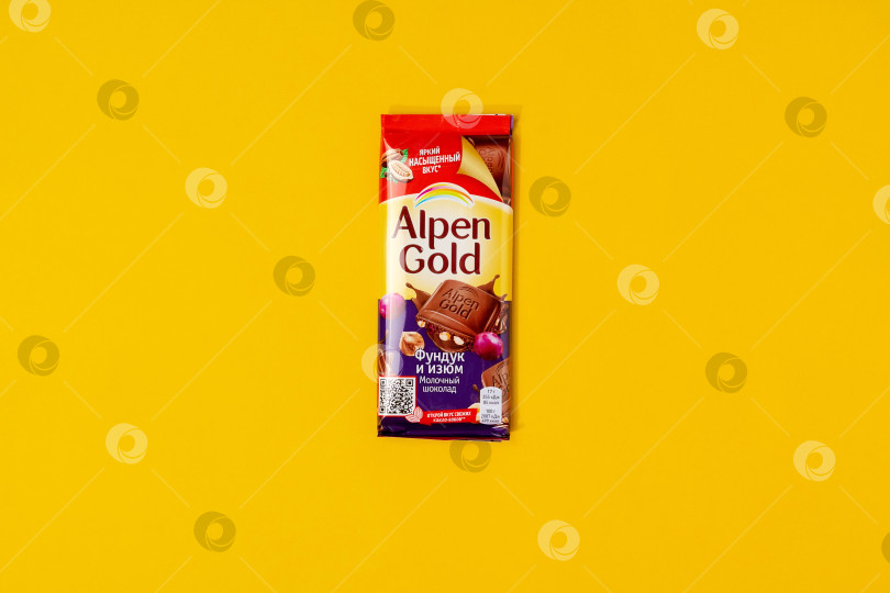 Скачать Тюмень, Россия - 25 мая 2021 года: Шоколад Alpen gold с фундуком и изюмом на желтом фоне фотосток Ozero