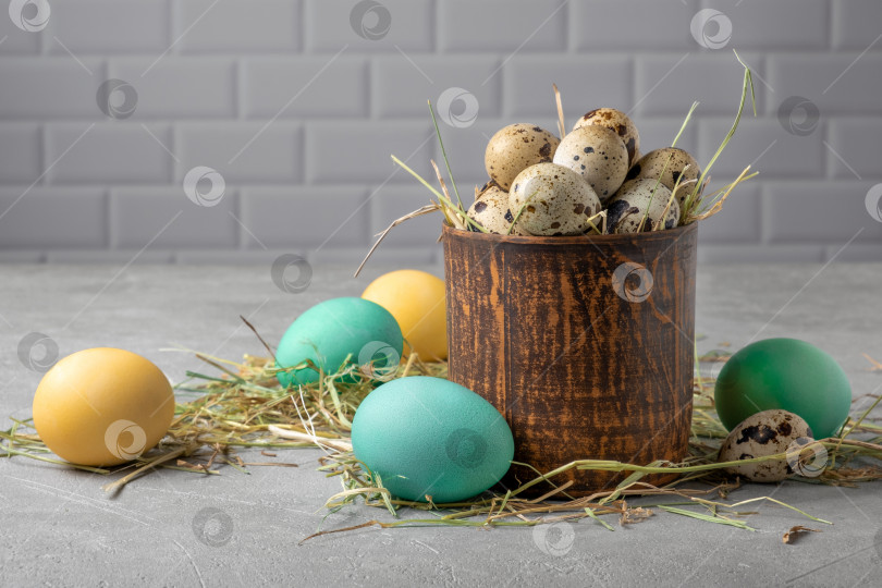 Скачать Глиняный сосуд с перепелиными яйцами в сене, окруженный раскрашенными куриными яйцами фотосток Ozero