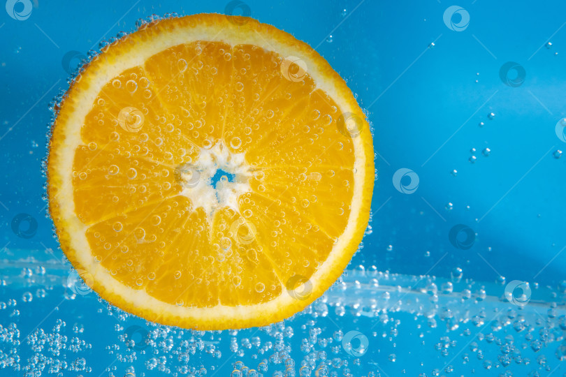 Скачать оранжевый фрукт в воде крупным планом. Освежающий грейпфрутовый напиток, коктейль. Замедленная съемка фотосток Ozero