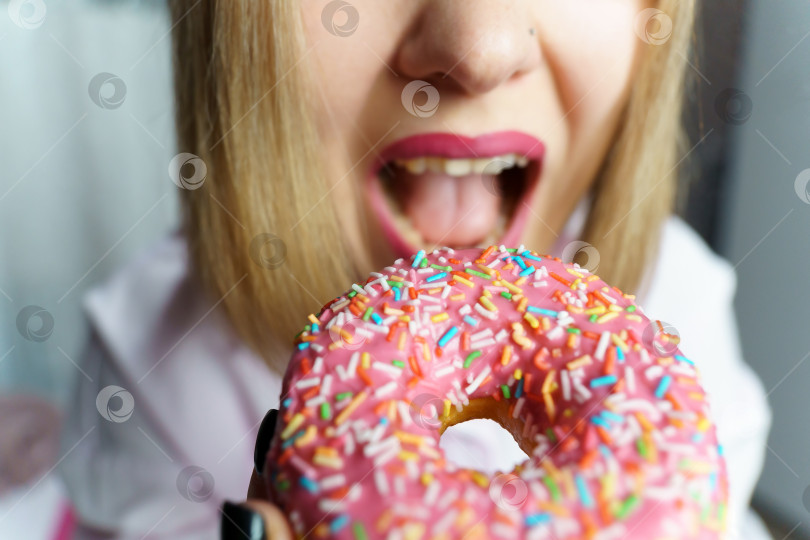Скачать Молодая женщина ест пончик крупным планом, выборочный фокус. Широкоугольный фотосток Ozero