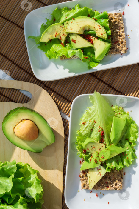 Скачать Полезный домашний тост с авокадо и солеными листьями салата. Цельная концепция питания. Вертикальная фотография фотосток Ozero