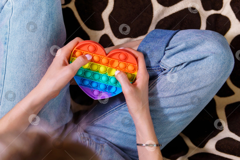 Скачать Девочка играет с разноцветной радужной игрушкой pop it. Избирательный фокус фотосток Ozero