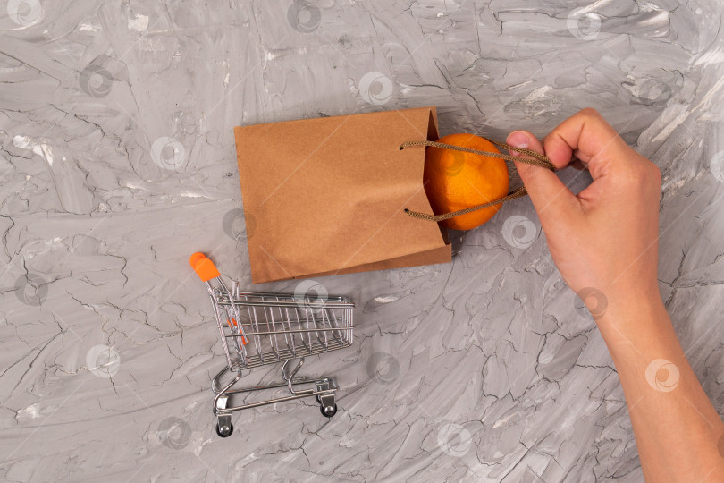 Скачать Тележка для покупок с крафтовым пакетом, покупаю фруктовые апельсины. фотосток Ozero