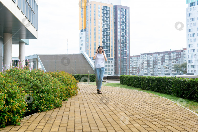 Скачать девочка-подросток танцует под музыку в наушниках, идя по улице фотосток Ozero