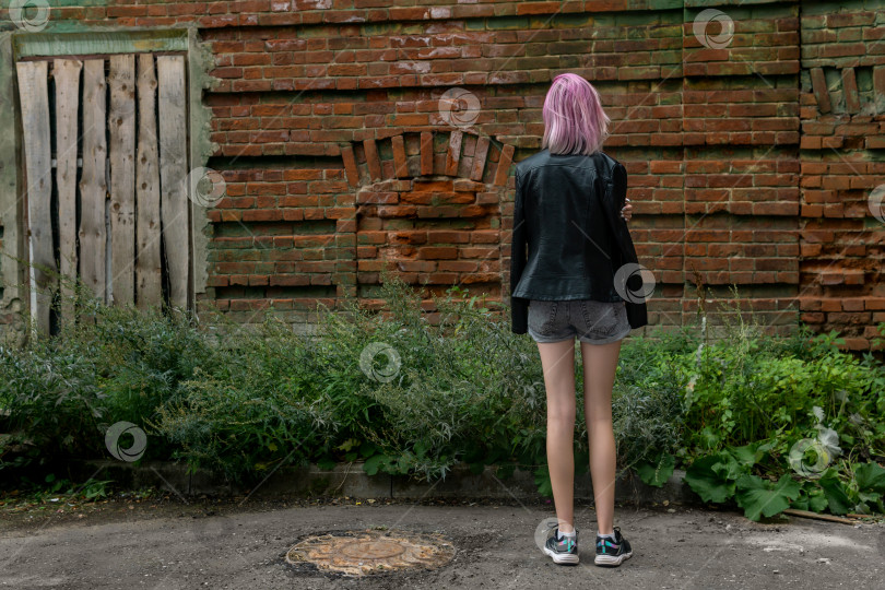 Скачать девочка-подросток, одиноко стоящая спиной к зрителю на фоне старой стены фотосток Ozero