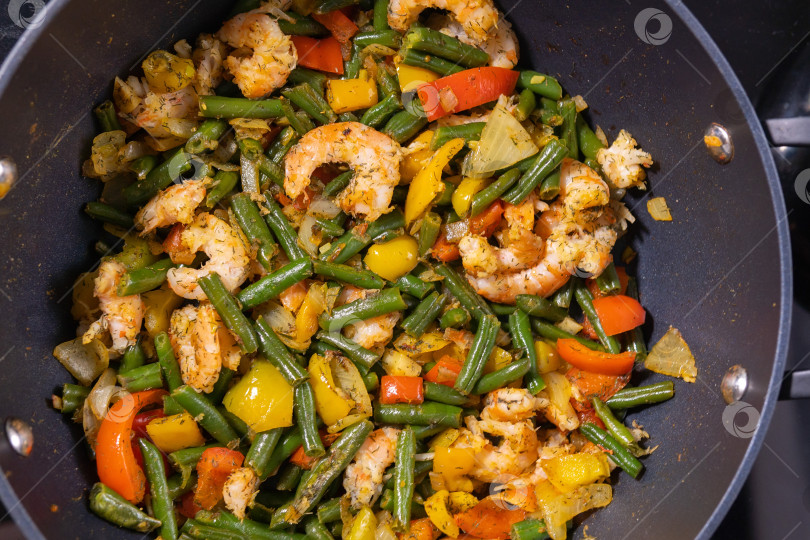 Скачать Обжарьте овощи с креветками крупным планом на сковороде. Приготовление пищи в домашних условиях фотосток Ozero