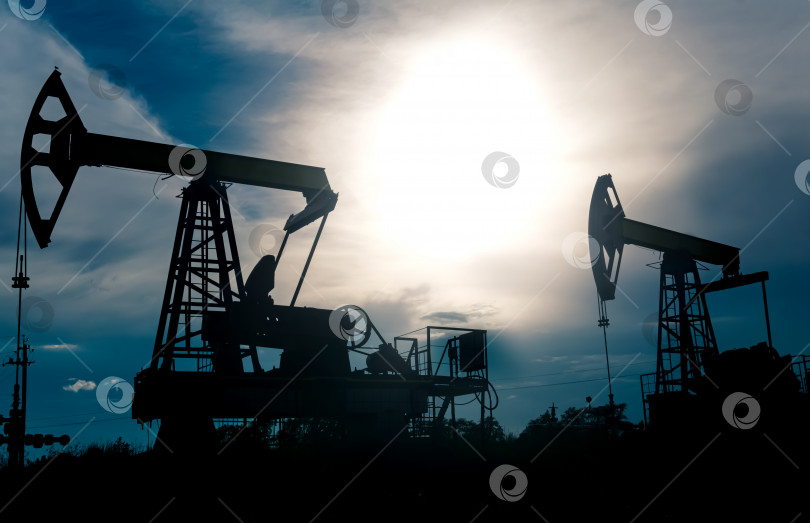 Скачать силуэты насосных станций на нефтяной скважине на фоне тревожного неба фотосток Ozero
