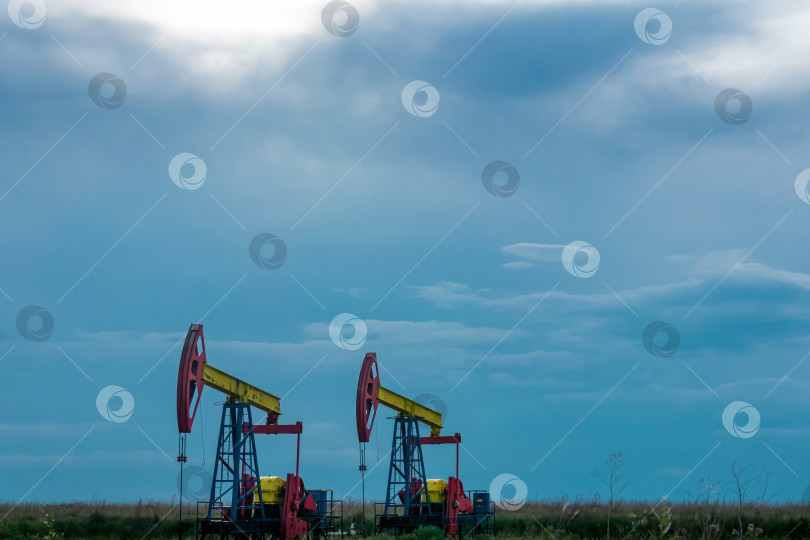 Скачать насосные установки, работающие на нефтяной скважине в поле под облачным небом фотосток Ozero
