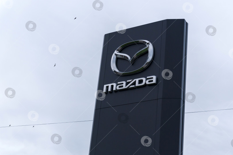 Скачать Волжский, Россия - 25 сентября 2021 года: Логотип Mazda - японского автопроизводителя, базирующегося в Хиросиме, Япония. Избирательный фокус фотосток Ozero