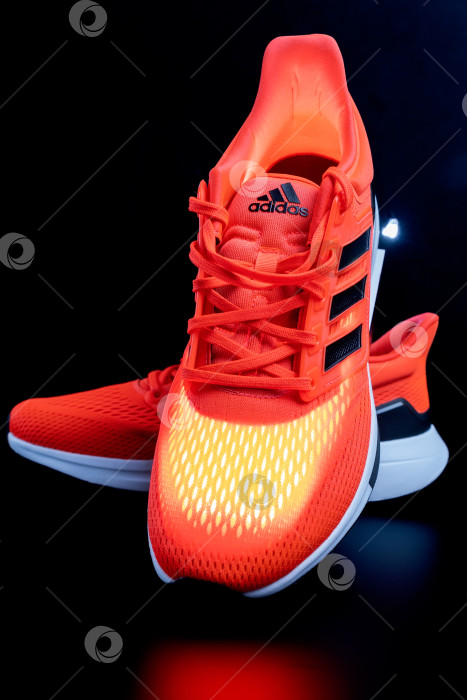 Скачать Тюмень, Россия - 13 ноября 2021 года: Новые кроссовки adidas оранжевого цвета. Логотип крупным планом. Вертикальная фотография фотосток Ozero