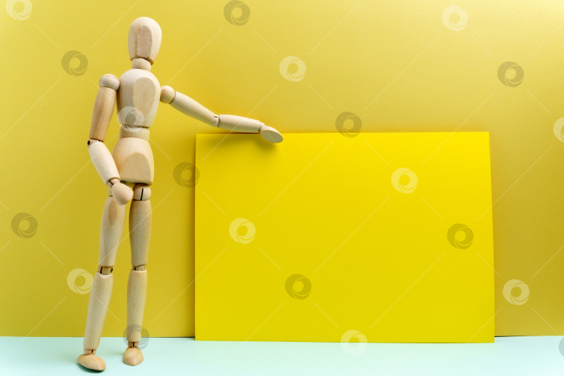 Скачать Деревянный человеческий манекен, говорящий или презентующий, говорящий стоя, пустое место для текста. Желтый фон фотосток Ozero