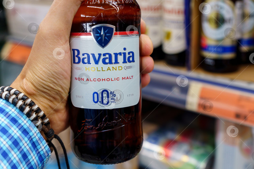 Скачать Волжский, Россия - 21 сентября 2021 года: Бутылка безалкогольного пива Bavaria Holland. В руках покупателя. Избирательный фокус фотосток Ozero