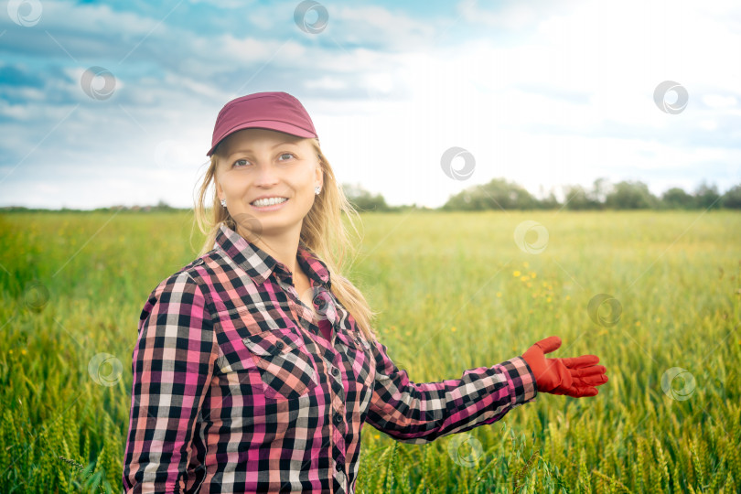Скачать улыбающаяся женщина-сельскохозяйственный работник показывает рукой на поле фотосток Ozero