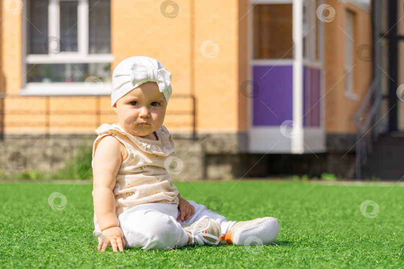 Скачать малыш-карапуз сидит на зеленой лужайке на фоне дома фотосток Ozero