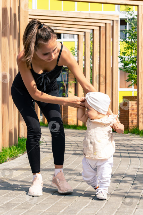 Скачать мама и маленькая дочь гуляют в городском дворе, ребенок учится ходить фотосток Ozero
