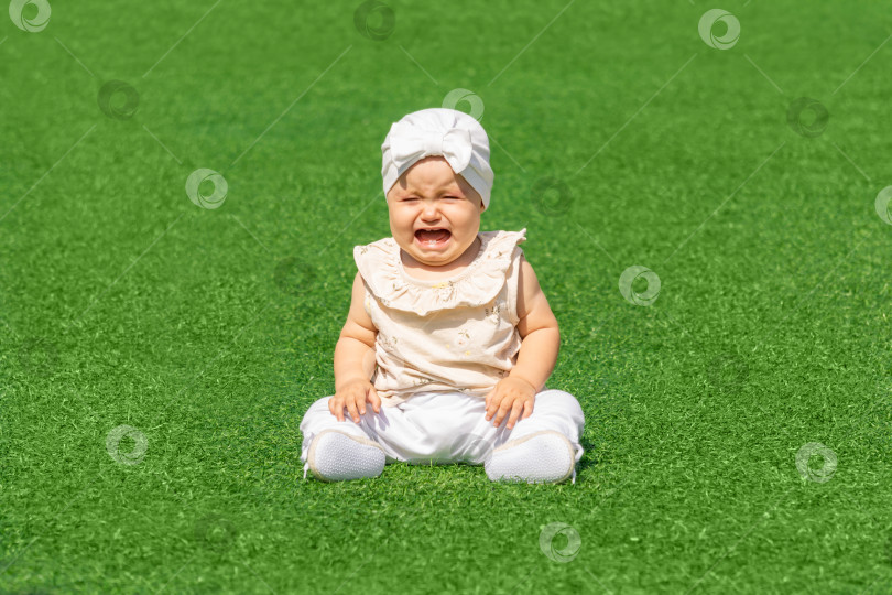 Скачать ребенок плачет, сидя посреди зеленой лужайки фотосток Ozero