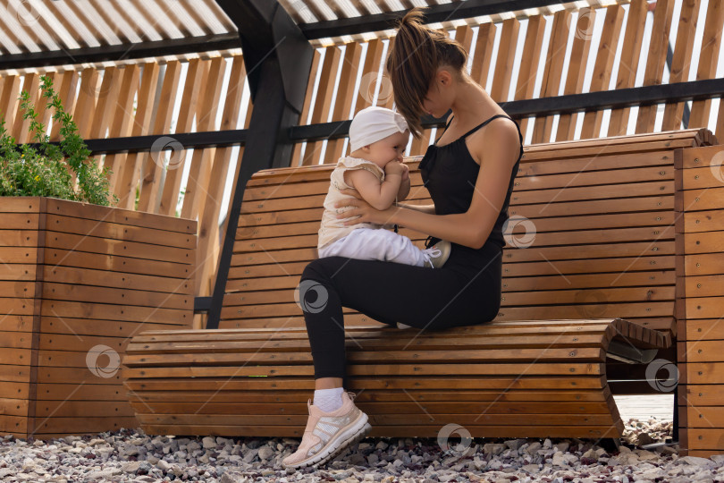 Скачать молодая мама со своей маленькой дочерью играют на скамейке в парке фотосток Ozero