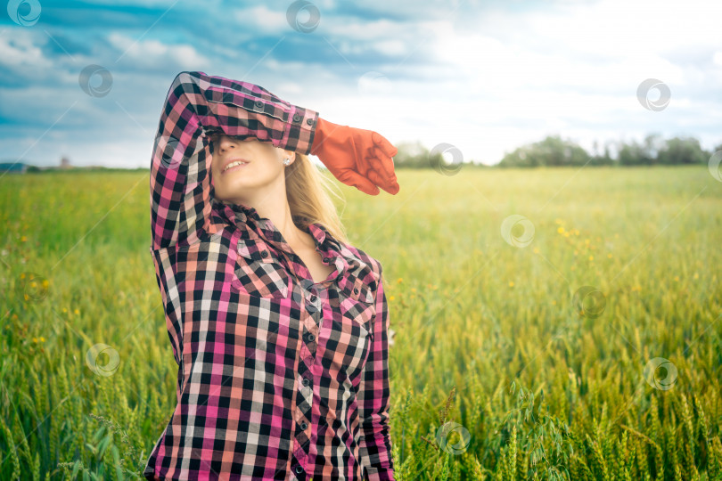 Скачать усталая женщина-сельскохозяйственный работник на фоне поля вытирает рукой пот со лба фотосток Ozero