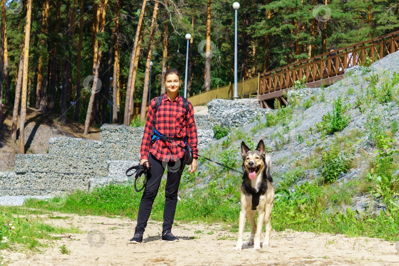 Скачать Молодая девушка в красной рубашке. Девушка с собакой. Прогулка с животным по лесу фотосток Ozero
