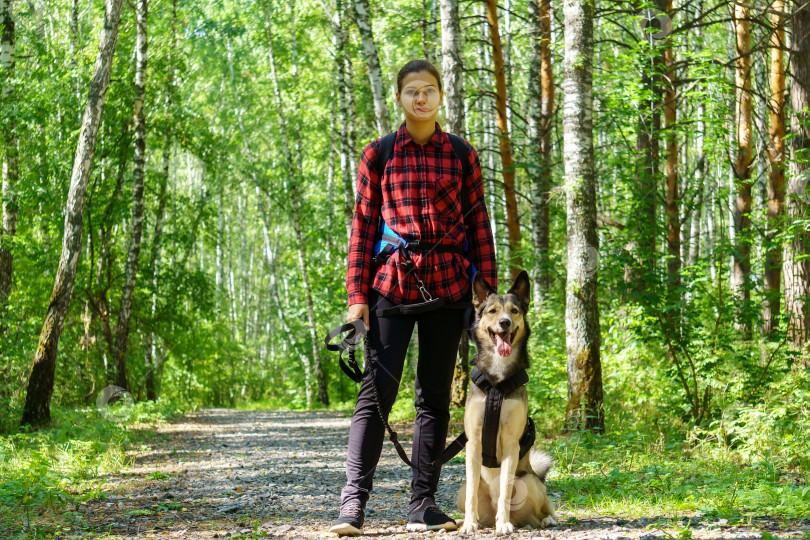 Скачать Молодая девушка в красной рубашке. Девушка с собакой. Прогулка с животным по лесу фотосток Ozero