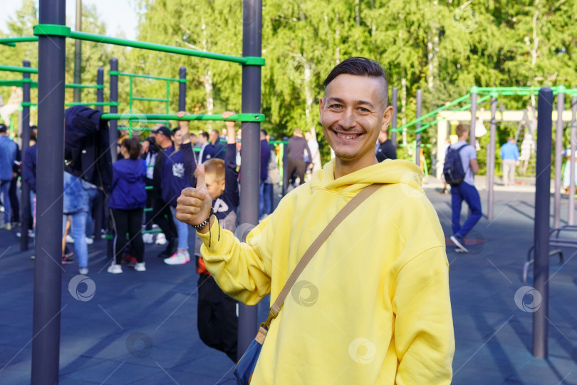 Скачать Молодой жизнерадостный мужчина в желтой куртке на спортивном мероприятии. Избирательный фокус фотосток Ozero