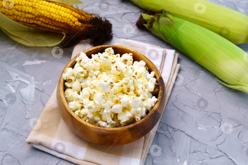 Скачать Вкусный традиционный попкорн и кукурузные початки на сером фоне фотосток Ozero