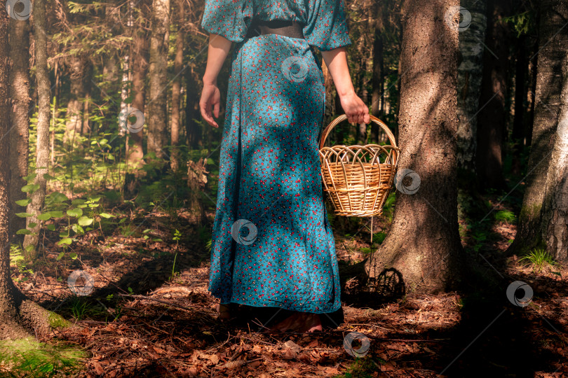 Скачать молодая женщина в народной крестьянской одежде с плетеной корзинкой прогуливается по темному лесу фотосток Ozero